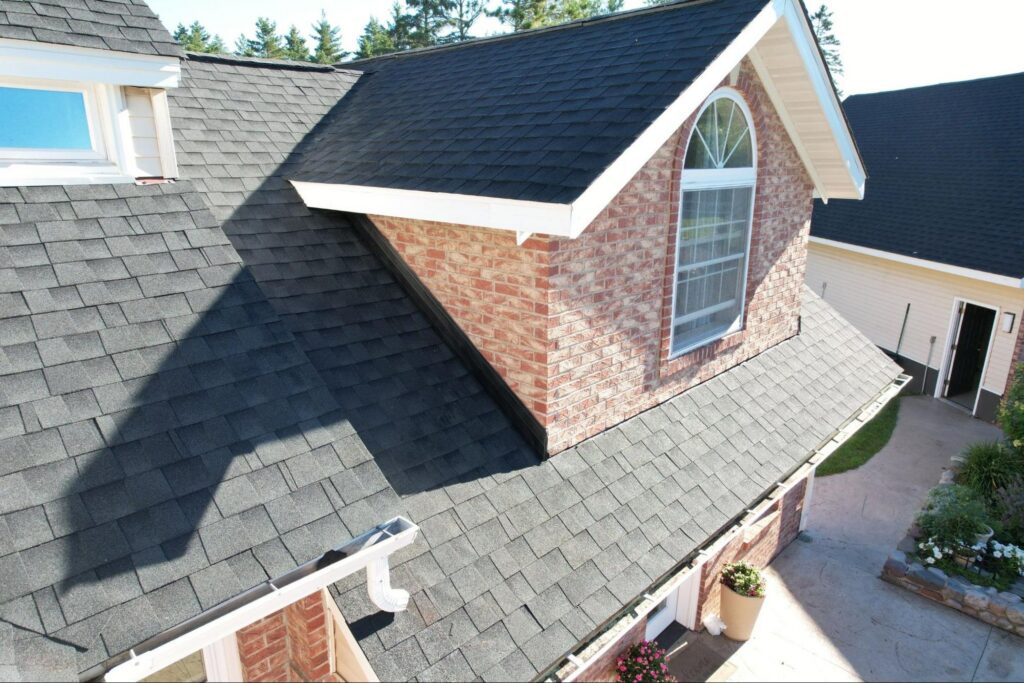 Close-up drone view of architectural asphalt shingles, dormer flashing, and gutters during an Empire Roofing roof inspection.