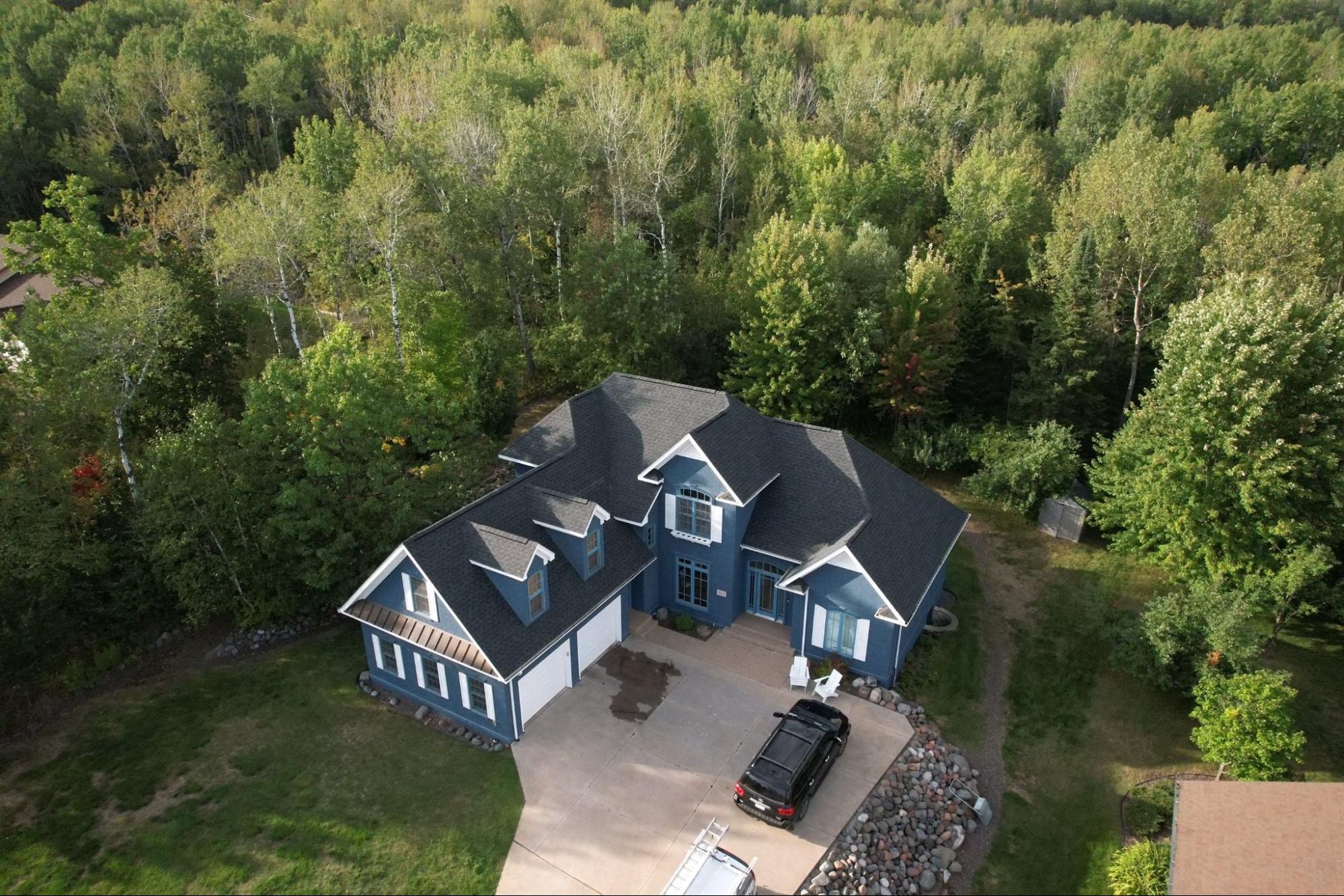 Completed asphalt shingle roof replacement on a wooded northern Minnesota home by Empire Roofing.