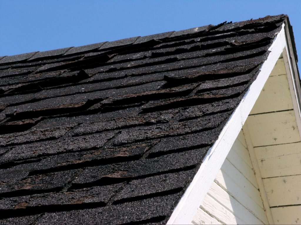 Roof inspection in Duluth, MN looking at the visibly damaged asphalt shingles.