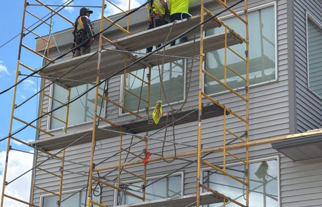 Empire Roofing crew installing gray vinyl siding on a multi-story Duluth building