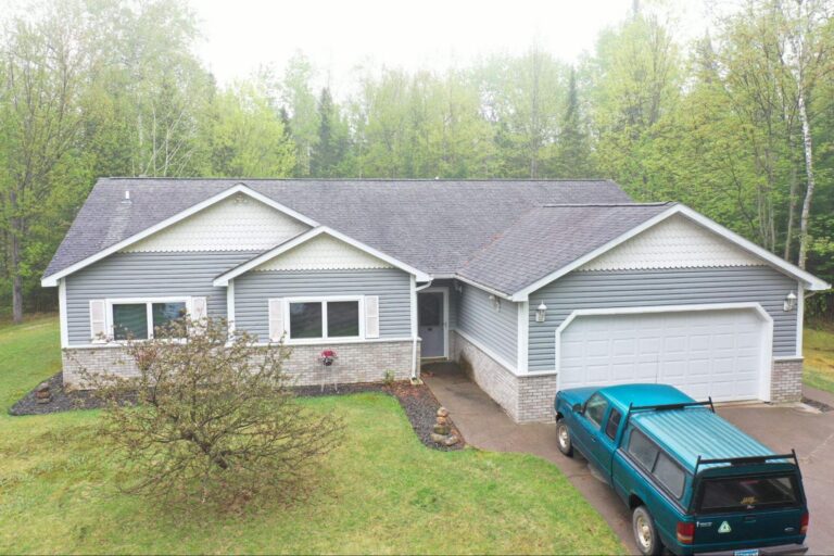 Gray vinyl siding installed by Empire Roofing on a single-story home with brick trim.