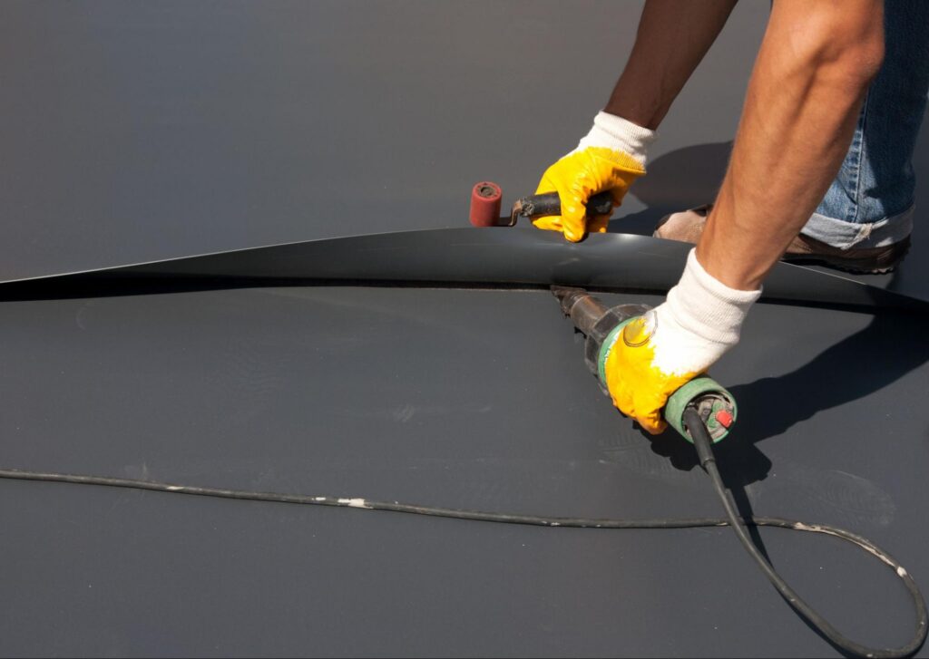 Roofer heat welding a membrane roofing seam on a low-slope roof in Duluth, MN.